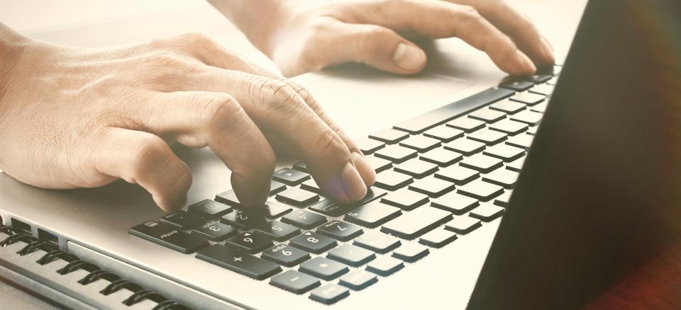 Hands typing on laptop keyboard