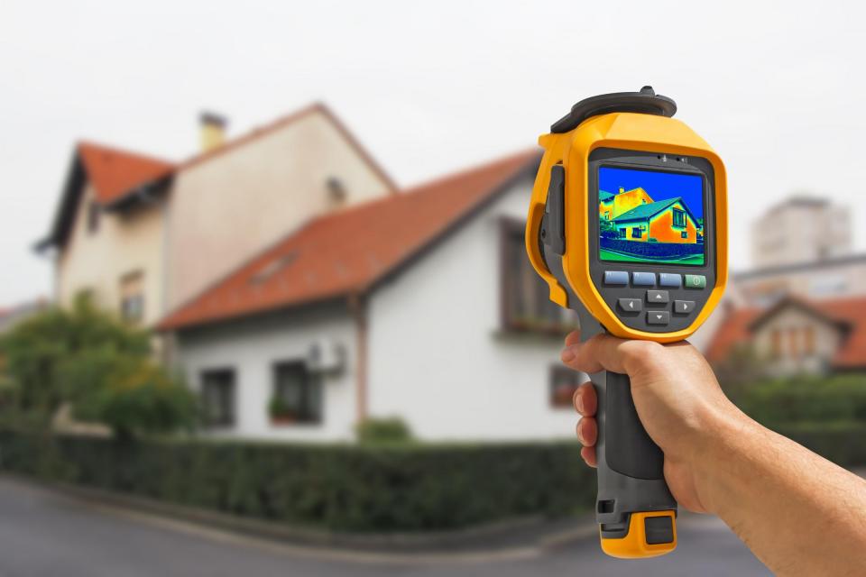 Hand Holding Thermal Imager in Front of House