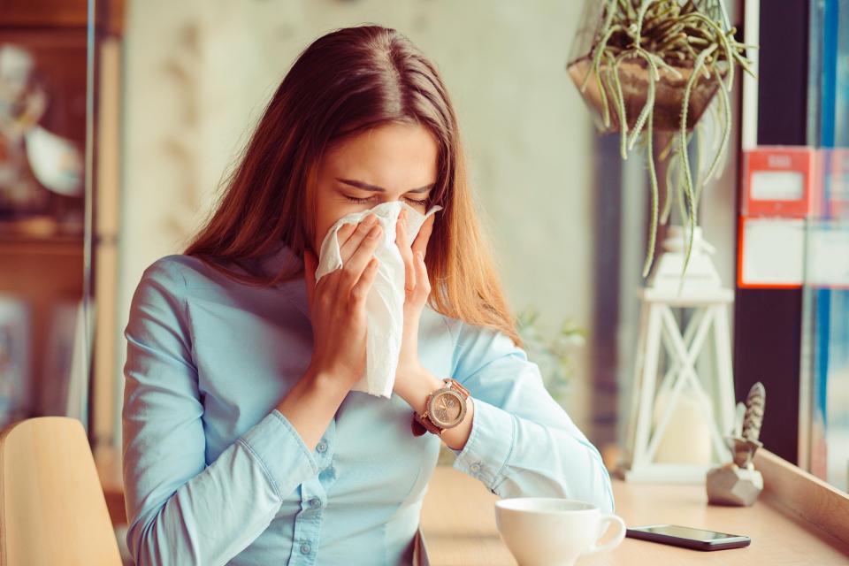 Woman sneezing into tissue